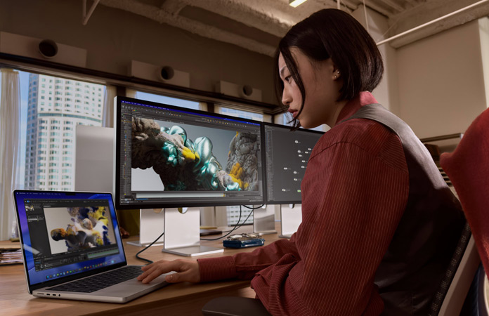 Iemand die in een kantooromgeving werkt met MacBook Pro, die is aangesloten op Studio Display XDR