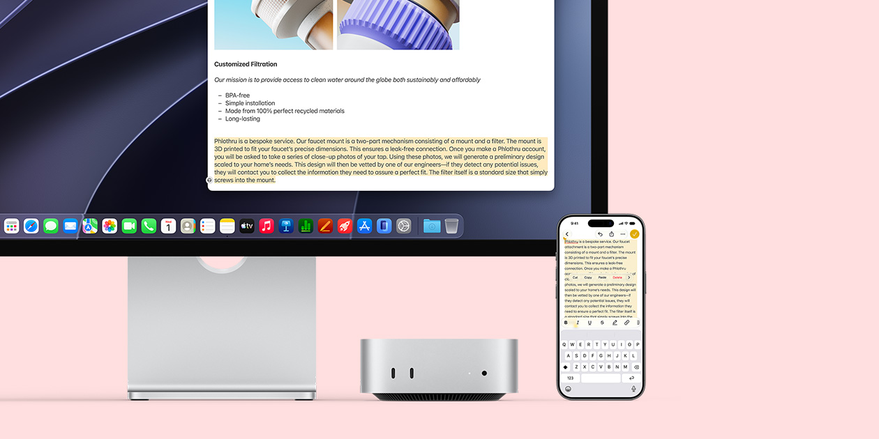 Bagian depan Mac mini, terselip di bawah Studio Display, sebuah iPhone berada di sebelah kanan perangkat dan layar, teks yang dipilih dengan perintah potong, salin, tempel, dan Isi-Auto di bagian atas iPhone cocok dengan teks yang disorot di layar, menampilkan Papan Klip Universal
