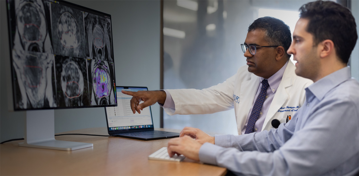 Dos personas de un equipo médico miran radiografías en un iMac.