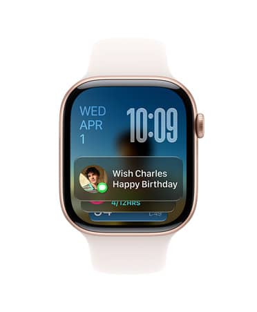Apple Watch Series 11 i rosaguld med rem i farven sart fersken. Urskiven viser datoen øverst til venstre, tidspunktet øverst til højre og Beskeder-widgetten nederst